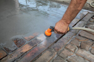 Cleaning concrete with a garden hose to remove excess dirt and debris.